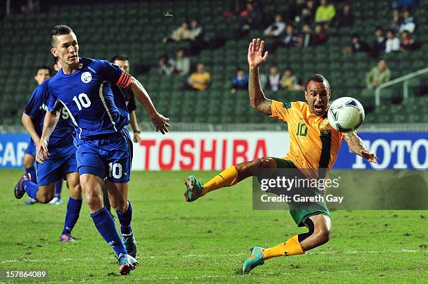 Archie Thompson of Australia is tackled by Jason Cunliffe of Guam during the EAFF East Asian Cup 2013 Qualifying match between Guam and Australia at...