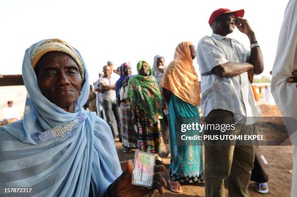 Eighty-year-old Aminatu Sulemana sits in a queue holding her voter's card at Maluwe polling station, Bole Bamboi constituency, in a northern region...