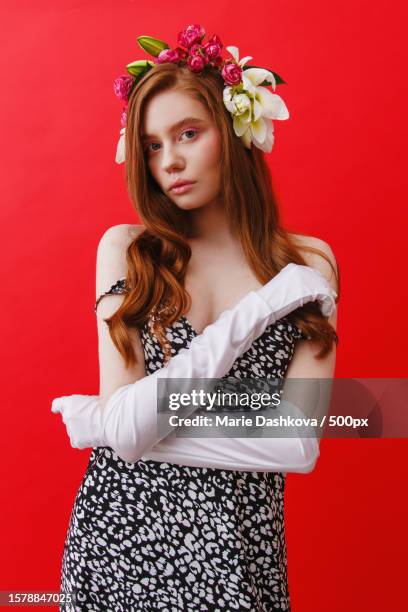 beautiful woman wearing fashion dress and elegant wreath against red background - editorial template stock pictures, royalty-free photos & images