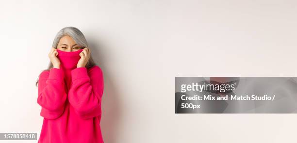 cheerful woman laughing,hiding face inside collar,copy space - editorial template stock pictures, royalty-free photos & images