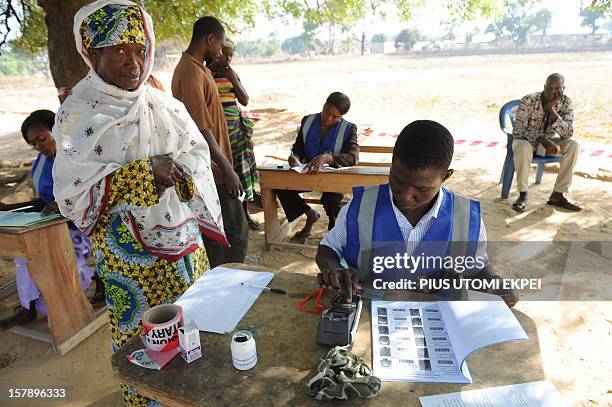 An electoral officer checks the identity of a voter at the Bole polling station, in the Bole Bamboi constituency of northern Ghana, on December 7,...