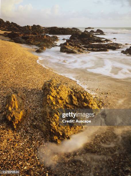 Tide ebbing as the sun rises on a rocky headland foreshore. On the horizon lie the Keppel Islands in the Great Barrier Reef Marine Park, and further...
