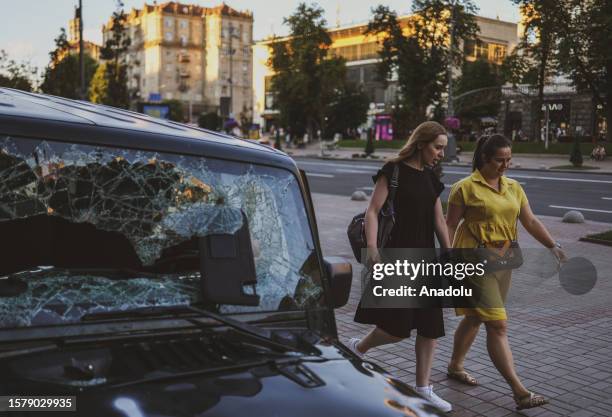Women walk past a vehicle with a broken front glass at a street during their daily life as Russia and Ukraine war continues in Kyiv, Ukraine on...