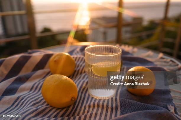 fresh summer lemonade outdoors on blue fabric on terrace with a view. fruits of lemon and lime. - softdrinks bottle stock-fotos und bilder