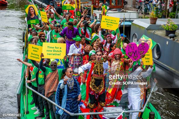 People from Suriname are seen participating on one of the boats during the event. The Canal Parade starts around noon and takes all afternoon. Around...