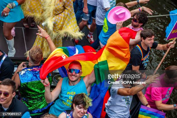 Man holding a rainbow flag is seen smiling to the camera during the event. The Canal Parade starts around noon and takes all afternoon. Around 80...