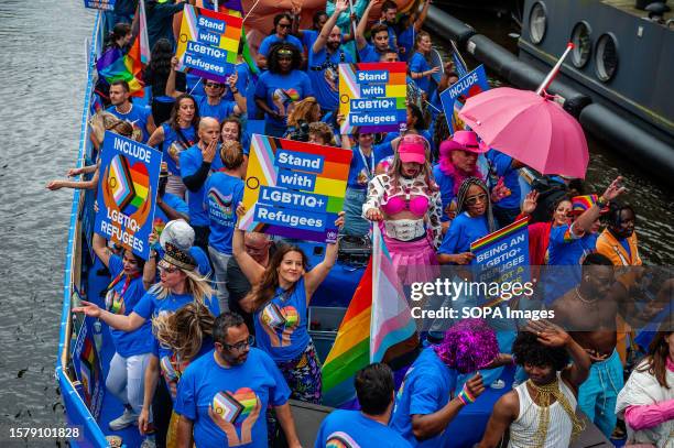 People are seen holding placards in support of LGBTQI+ refugees during the event. The Canal Parade starts around noon and takes all afternoon. Around...