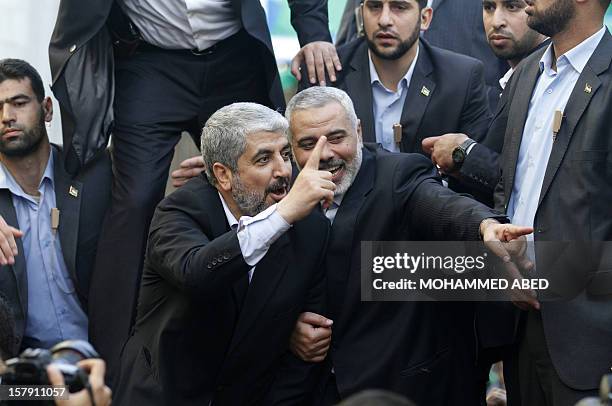 Hamas leader-in-exile Khaled Meshaal and Hamas leader in the Gaza Strip Ismail Haniya wave from the rooftop of a vehicle during a parade following...