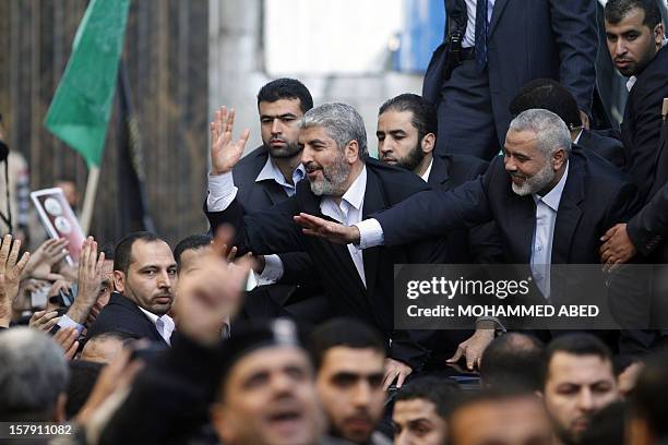 Hamas leader-in-exile Khaled Meshaal and Hamas leader in the Gaza Strip Ismail Haniya wave from the rooftop of a vehicle during a parade following...