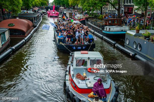 Woman is seen sitting at the front of one of the boats during the event. The Canal Parade starts around noon and takes all afternoon. Around 80 boats...