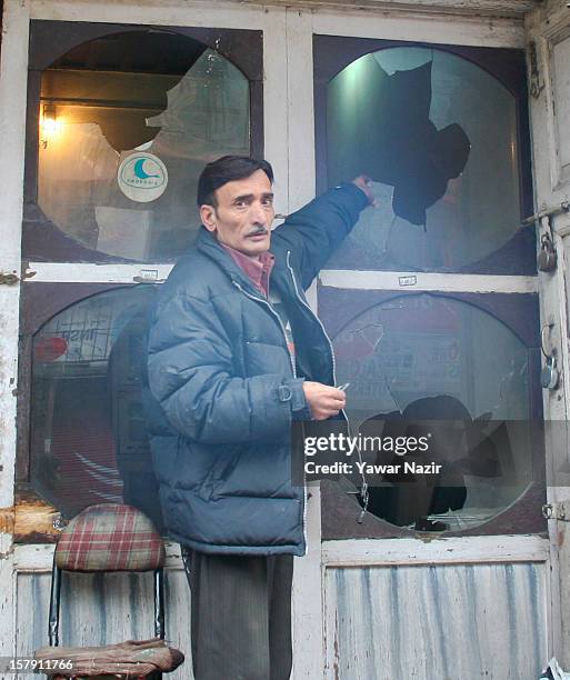 The assistant of a dentist inspects broken window panes of their building which were damaged by Indian policemen during a protest against a court...