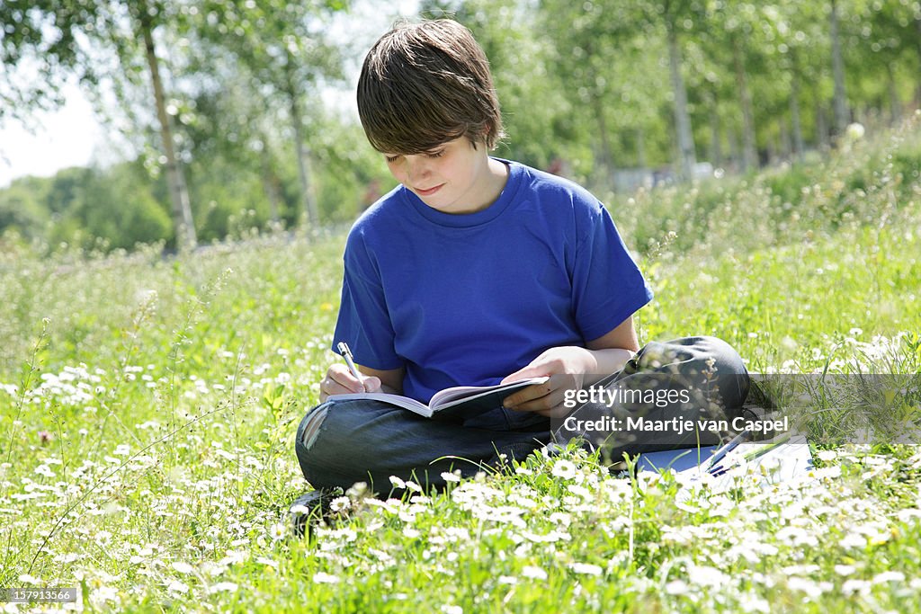 Garçon assis et écrire en herbe