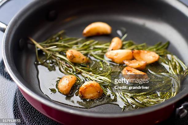 sauteed garlic and rosemary in olive oil - olijfolie stockfoto's en -beelden
