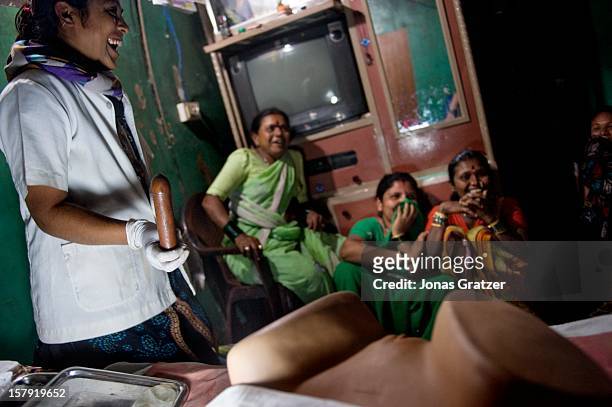 Female sex workers in a brothel, start laughing when a nurse, Surekha Khairnar who is 27 years old, takes out a dummy penis to demonstrate various...