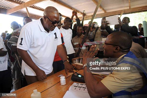 An electoral commission official checks the identification of the ruling National Democratic Congress president and presidential candidate John...