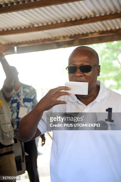 Ghana's ruling National Democratic Congress president and presidential candidate John Dramani Mahama kisses his ballot prior to cast his vote at the...