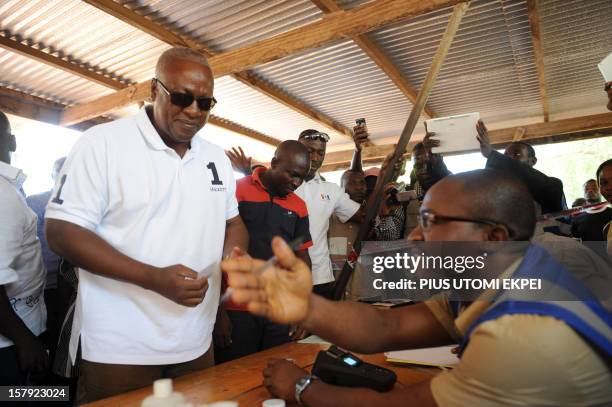 An electoral commission official checks the identification of the ruling National Democratic Congress president and presidential candidate John...