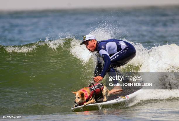 Skylar and owner Homer Henard catch a wave while competing in the tandem category of the World Dog Surfing Championships in Pacifica, California, on...