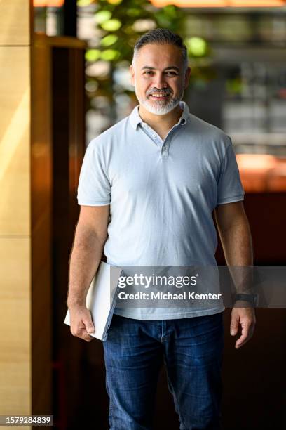 smiling mature businessman with laptop standing in a corridor - polo shirt stock pictures, royalty-free photos & images