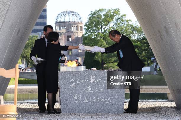 Hiroshima Mayor Kazumi Matsui and representatives of bereaved families enshrine a list of the atomic bomb victims at the cenotaph during a ceremony...