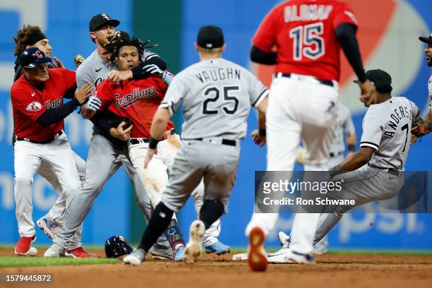 Jose Ramirez of the Cleveland Guardians is restrained as Tim Anderson of the Chicago White Sox falls to the ground during a fight in the sixth inning...