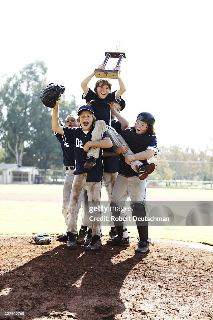 Little league team celebrating with trophy.