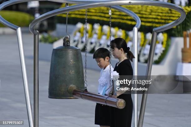 School children and an adult prepare to ring the gong at the Peace Memorial Park during a ceremony to pay tribute for the atomic bomb victims in...