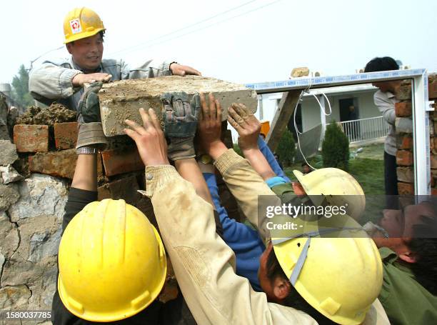 Chinese workers lay a slab of brick on a wall surrounding the hospital erected in barely a week to house a rapidly increasing number of Chinese...