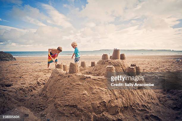two little boys building sandcastle on beach - children only stock-fotos und bilder
