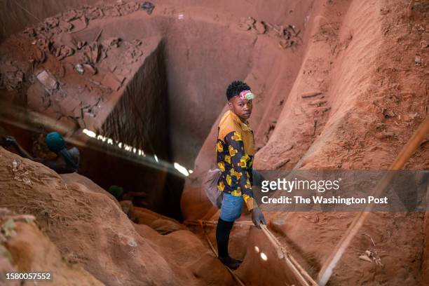 An artisanal miner descends into a pit to bring a bag with bottles of water for miners working underground at the Kamilombe artisanal mine, near the...
