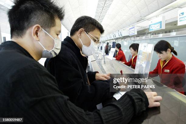 Travellers wear masks to protect against a mysterious outbreak of pneumonia as they check-in for a Cathay Pacific flight at Hong Kong's Chek Lap Kok...