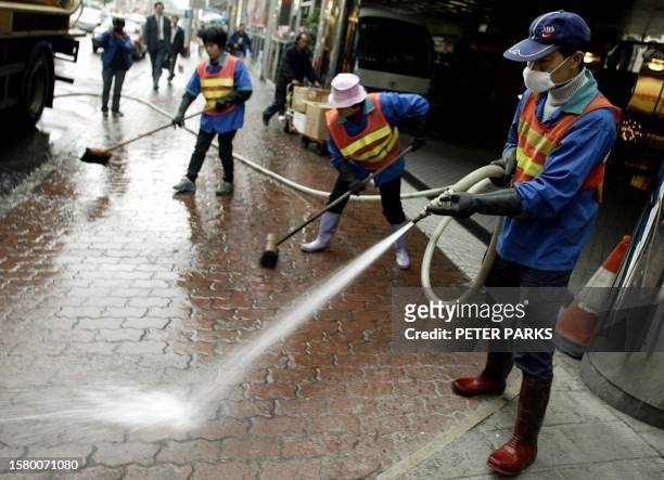 Workers hose down the area outside the Metropole Hotel in Hong Kong where a mystery pneumonia is believed to have started that has swept across Asia,...