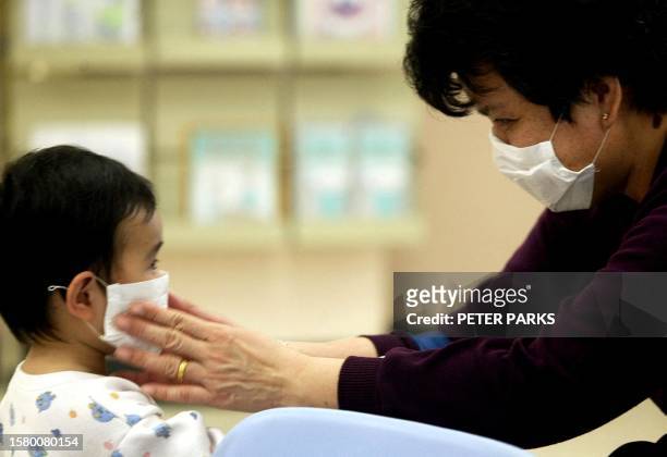 Mother puts a mask on her son at the Prince of Wales Hospital in Hong Kong, 17 March 2003, to protect against a mysterious outbreak of pneumonia...