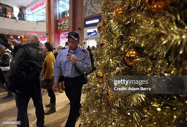 Police officer speaks on a walkie-talkie to help maintain crowd control during Christmas shopping at a shopping mall on December 8, 2012 in Berlin,...