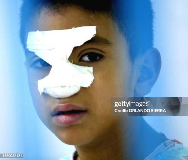 Eight year old Patrick Guevara, looks through a window at the Hospital Materno Infantil in Tegucigalpa, while he recovers from dengue, 16 July 2002....