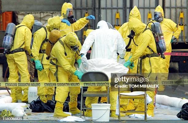 Members of a haz-mat response team, help to remove a hazardous materials suit from an investigator who had emerged from the US Post Office in West...