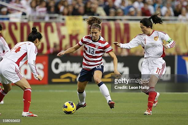 Alex Morgan of Team USA dribbles the ball against Dongni Wang and Wei Pu of China during the first half of the game at Ford Field on December 8, 2012...