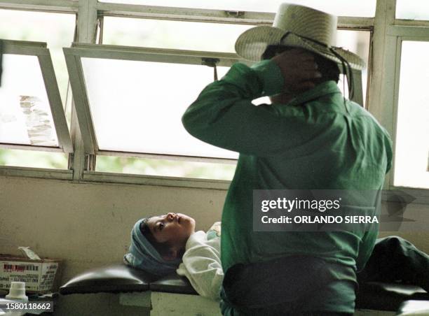 Farm worker looks at his son 29 June 1999 who is suffering from dengue fever in Tegucigalpa. Un campesino observa el 29 de Junio de 1999 a su hijo,...