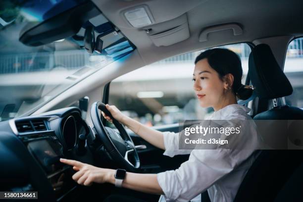 young asian woman sitting in car and touching screen, setting up gps navigation system for her destination. on the move. car rental. transportation with technology concept - car rental stock pictures, royalty-free photos & images