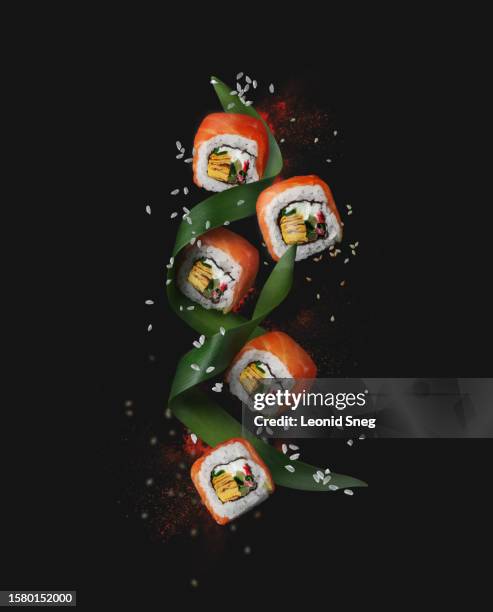 flying maki sushi on black background. food levitation concept - freeze motion stock-fotos und bilder