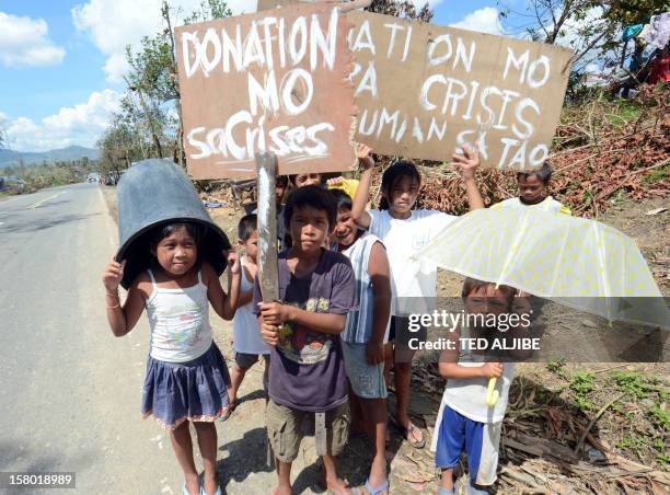 Children, victims of devastating Typhoon Bopha, beg for alms along a roadside in the town of Osmena in Compostela Valley province on December 9, 2012...