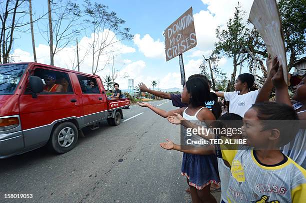 Children, victims of devastating Typhoon Bopha, beg for alms along a roadside in the town of Osmena in Compostela Valley province on December 9, 2012...
