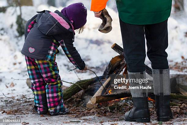 Man and young child warm themselves next to a camp fire after choosing and cutting down their Christmas tree in a forest on on December 8, 2012 in...