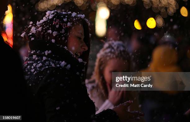 People react to a snow machine as they gather to look at Christmas festive lights that adorn a detached house in a suburban street in Melksham,...