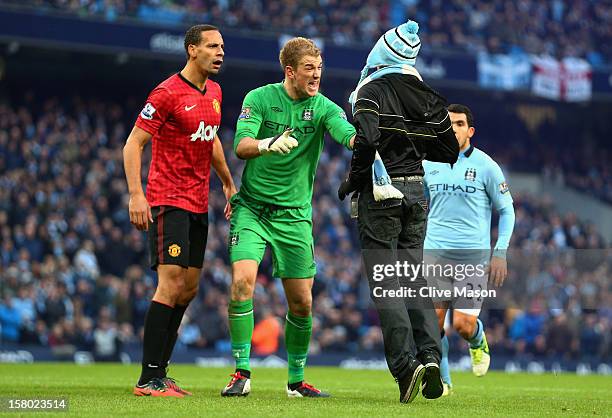 Joe Hart of Manchester City confronts a pitch invader during the Barclays Premier League match between Manchester City and Manchester United at the...