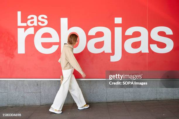 Woman walks past a large banner announcing the Summer sale season outside the Spanish biggest department store El Corte Ingles in Spain.