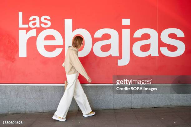 Woman walks past a large banner announcing the Summer sale season outside the Spanish biggest department store El Corte Ingles in Spain.