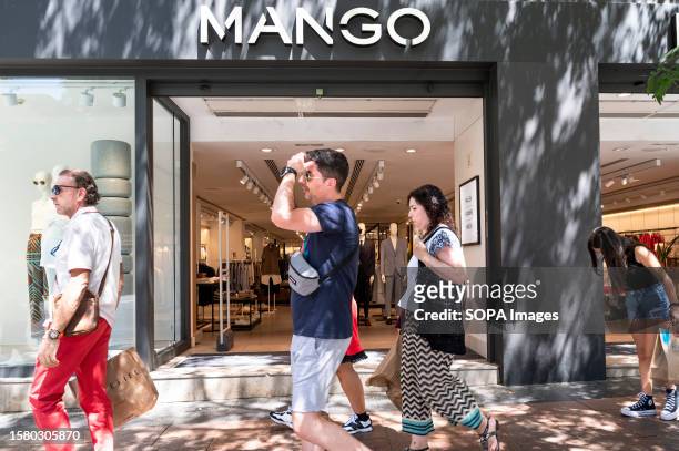Pedestrians walk past the Spanish multinational clothing brand Mango store in Spain.