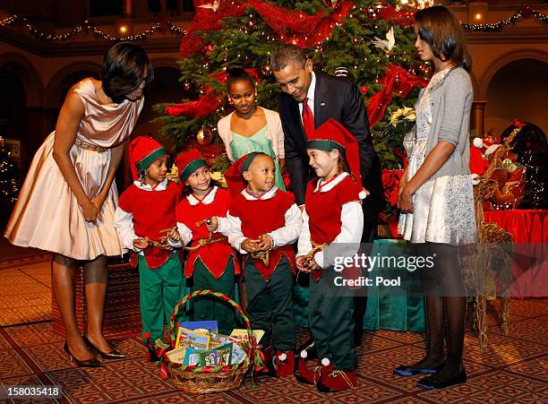 President Barack Obama , first lady Michelle Obama , and daughters Malia and Sasha greet Christmas elves as they attend the "Christmas in Washington"...
