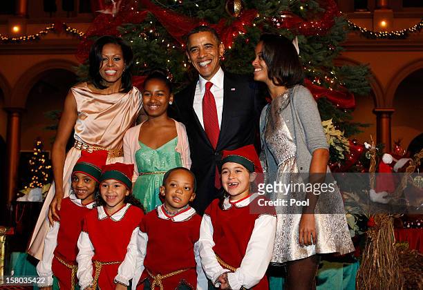 President Barack Obama , first lady Michelle Obama , and daughters Malia and Sasha greet Christmas elves as they attend the "Christmas in Washington"...
